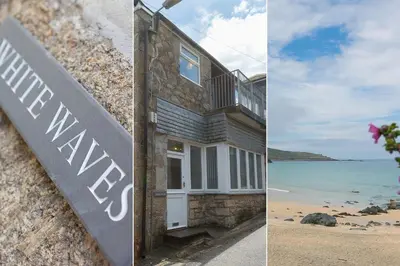 a house on the beach next to a sign at White Waves in St Ives