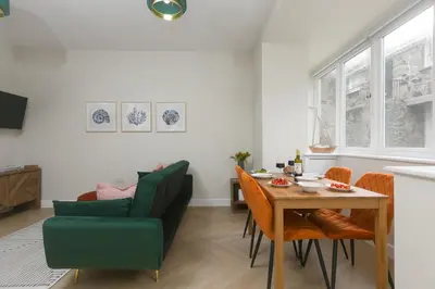 a living room with a table and a green chair at White Waves in St Ives