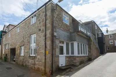 an old brick building with white doors and windows at White Waves in St Ives