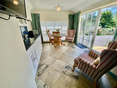 a kitchen and living room with a table and chairs at Lynwood House Self Contained Studio in Tregoney