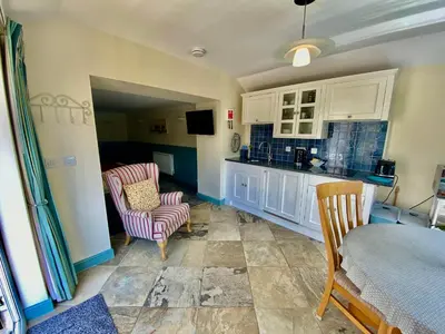 a kitchen with a table and two chairs and a counter at Lynwood House Self Contained Studio in Tregoney