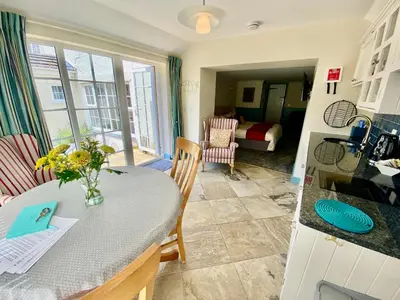 a kitchen and living room with a table and chairs at Lynwood House Self Contained Studio in Tregoney