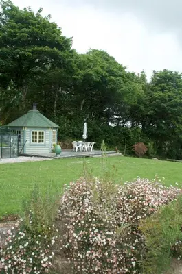 a garden with a table and a bench in a park at The Old Deer House in Bodmin
