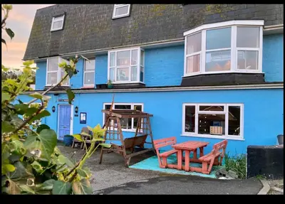 a blue house with chairs and a table in front of it at Blue Room Hostel Newquay in Newquay