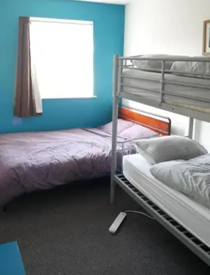 a bedroom with two bunk beds and a window at Blue Room Hostel Newquay in Newquay