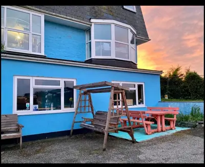 a blue house with a picnic table and a ladder at Blue Room Hostel Newquay in Newquay