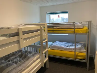 a room with three bunk beds and a window at Blue Room Hostel Newquay in Newquay