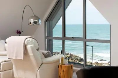 a white chair in a room with a view of the ocean at Fistral Beach Penthouse, Newquay in Crantock