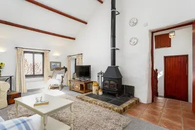 a living room with a wood stove in it at The Snug at Cornish Barn Holidays in Truro