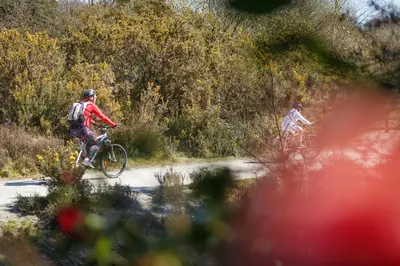 two people riding bikes on a dirt road at The Snug at Cornish Barn Holidays in Truro