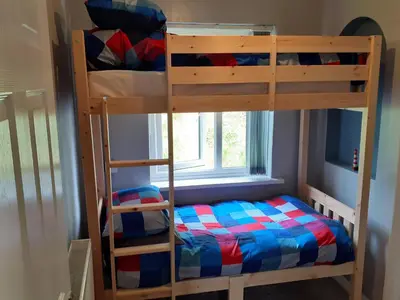 two bunk beds in a room with a window at Admirals Apartment 'As seen in Beyond Paradise ' sleeps 6 adults in Looe