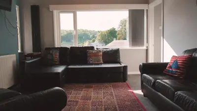 a living room with a black couch and a window at Admirals Apartment 'As seen in Beyond Paradise ' sleeps 6 adults in Looe