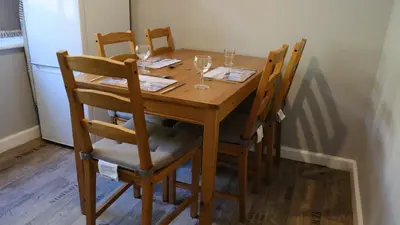 a wooden table with four chairs and wine glasses at Admirals Apartment 'As seen in Beyond Paradise ' sleeps 6 adults in Looe