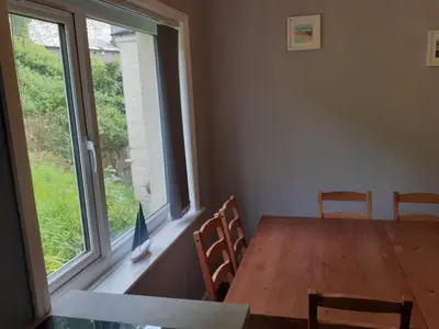 a dining room with a table and a large window at Admirals Apartment 'As seen in Beyond Paradise ' sleeps 6 adults in Looe