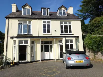 a white house with a car parked in front of it at Admirals Apartment 'As seen in Beyond Paradise ' sleeps 6 adults in Looe
