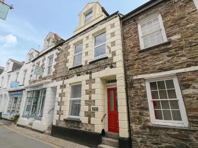 a stone house with a red door on a street at Pirate's Pad in St Austell