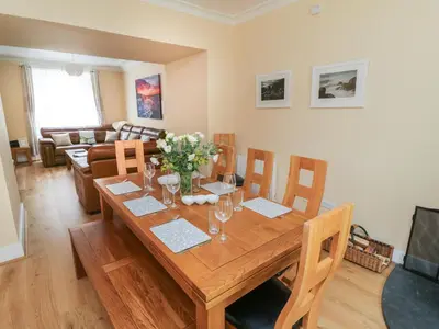 a dining room with a wooden table with flowers on it at Pirate's Pad in St Austell