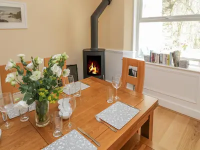 a table with a vase of flowers and a fireplace at Pirate's Pad in St Austell