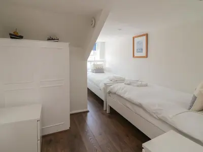 two beds in a room with white walls and wooden floors at Pirate's Pad in St Austell