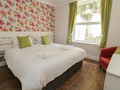 a bedroom with a large bed and a red chair at Pirate's Pad in St Austell
