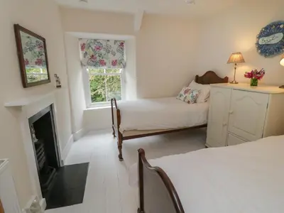 a bedroom with two beds and a fireplace at Fairfield Cottage in Boscastle