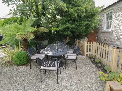 a patio with a table and chairs in a garden at Fairfield Cottage in Boscastle