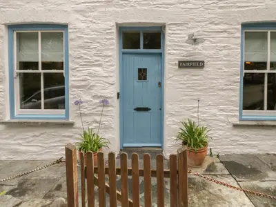 a house with a blue door and a fence at Fairfield Cottage in Boscastle