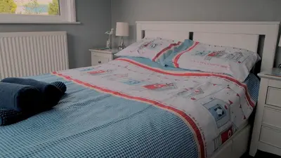 a bed with a blue and white comforter on it at Captain's Quarters 'As seen in Beyond Paradise ' in Looe