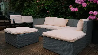 two wicker chairs with pillows on a patio with flowers at Captain's Quarters 'As seen in Beyond Paradise ' in Looe