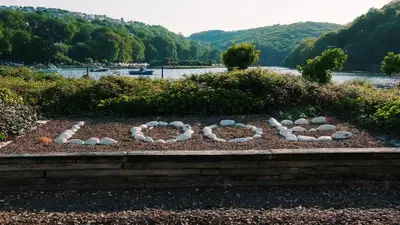 a peace sign in a garden next to a river at Captain's Quarters 'As seen in Beyond Paradise ' in Looe