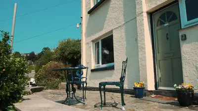 two chairs and a table in front of a building at Bosons Bunks 'As seen in Beyond Paradise ' in Looe