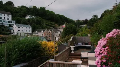 a wooden deck with chairs and flowers in a town at Bosons Bunks 'As seen in Beyond Paradise ' in Looe
