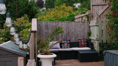 a patio with a bench with pillows on a fence at Bosons Bunks 'As seen in Beyond Paradise ' in Looe