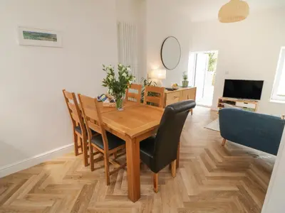 a dining room with a wooden table and chairs at Through The Porthole in Falmouth