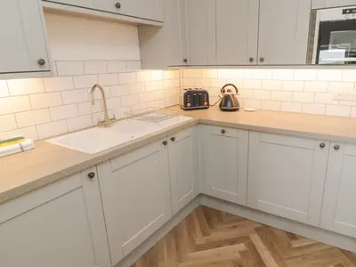 a kitchen with white cabinets and a sink at Through The Porthole in Falmouth