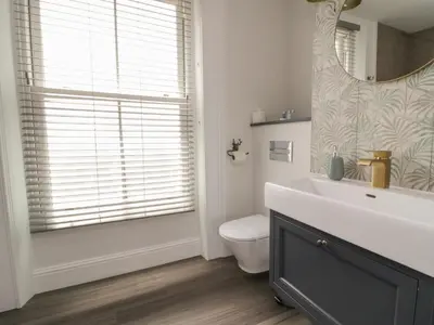 a bathroom with a sink and a toilet and a mirror at Through The Porthole in Falmouth
