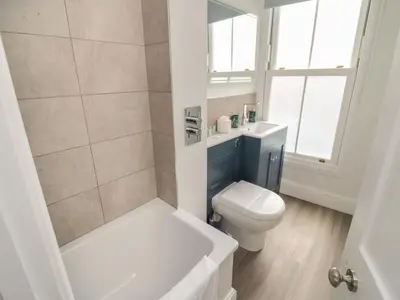 a bathroom with a tub and a toilet and a sink at Through The Porthole in Falmouth