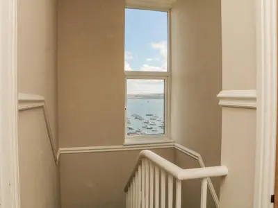 a staircase with a large window in a house at Through The Porthole in Falmouth