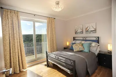a bedroom with a bed and a large window at Redcliffe House in Looe