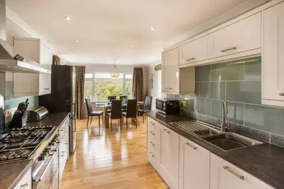 a kitchen with white cabinets and a dining room at Redcliffe House in Looe