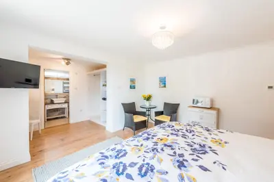 a bedroom with a large bed and a kitchen at Mandalay in Bude