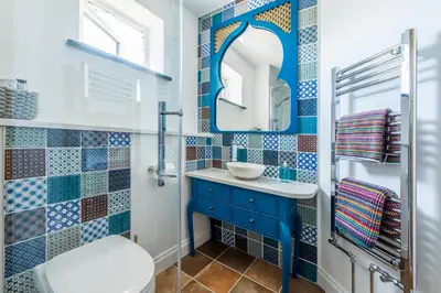 a bathroom with a blue and white tiled wall at Mandalay in Bude