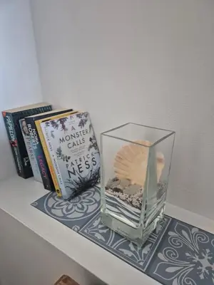 a glass vase sitting on a shelf with books at Number 6 in St Austell
