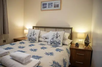 a bed with blue and white sheets and pillows at Harbourside Apartment in Mevagissey