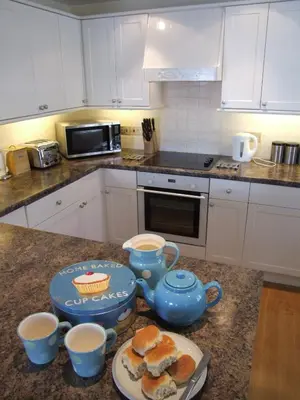 a kitchen with a table with tea pots and sandwiches at Harbourside Apartment in Mevagissey