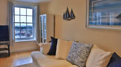 a living room with a couch and two windows at Harbourside Apartment in Mevagissey
