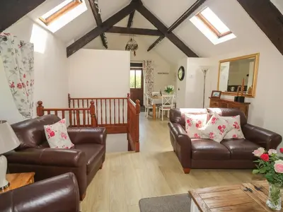 a living room with leather furniture and a ceiling with skylights at The Hayloft in Liskeard
