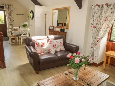 a living room with a leather couch and a table at The Hayloft in Liskeard