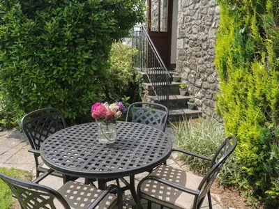 a table and chairs with a vase of flowers on it at The Hayloft in Liskeard