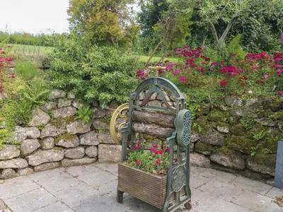 a garden seat with flowers in it next to a stone wall at The Hayloft in Liskeard